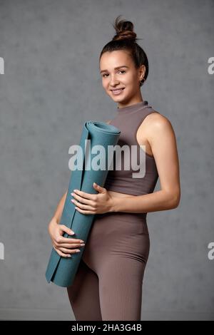 Donna incinta sorridente in abbigliamento sportivo pronto per la ginnastica mattutina o l'esercizio fisico. Giovane donna felice seguire stile di vita sano durante la gravidanza, tenere yoga Foto Stock