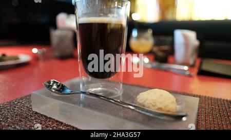 Caffè e un biscotto su un vassoio su un tavolo rosso W Bangkok Foto Stock