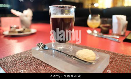 Caffè e un biscotto su un vassoio su un tavolo rosso W Bangkok Foto Stock