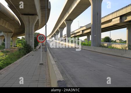 Ingresso dell'autostrada con segnale del traffico limite di velocità, strada in cemento in campagna con cielo blu. Foto Stock