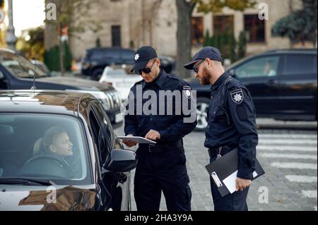 Poliziotti maschi che controllano la patente di guida Foto Stock