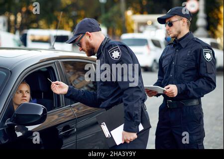 Poliziotti maschi che controllano la patente di guida Foto Stock