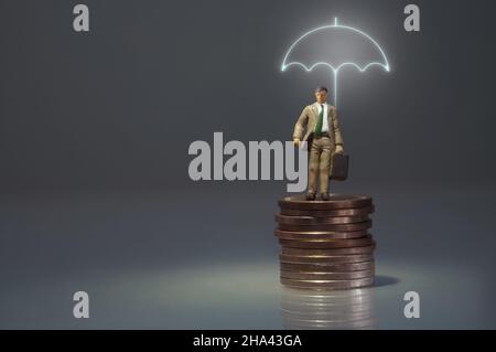 Uomo in miniatura in piedi sotto un ombrello illuminato in cima a un mucchio di monete Foto Stock