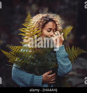 la gente e la natura amano concetto lifestyle. donna che abbraccia la foglia di pianta grande nei boschi con cura e protezione. ambiente ed esterno cambiamento climatico concetto di riscaldamento Foto Stock