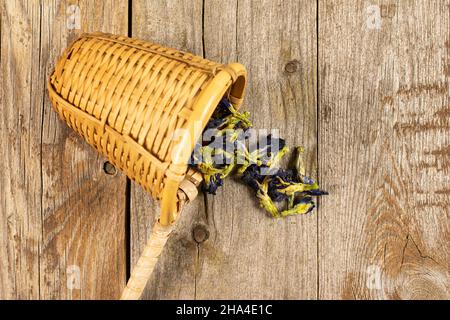 Lotto di clitoria ternatea secca intera con setaccio di bambù su legno vecchio Foto Stock