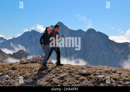 giovane coppia in un'escursione alla zugspitze 2962 m, sullo sfondo il falò con 2744 m la seconda montagna più alta in germania, wetterstein montagne garmisch-partenkirchen, alta baviera, baviera, germania meridionale, germania, europa, Foto Stock