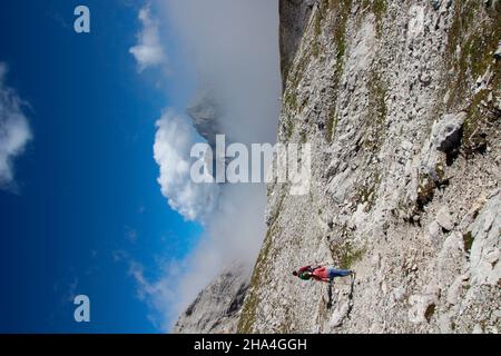 giovane coppia escursioni,discesa dal zugspitze 2962 m, wetterstein montagne cielo blu, nuvole, umore nuvoloso,il hochwanner 2744 m picchi attraverso le nuvole,garmisch-partenkirchen,loisachtal,alta baviera,baviera,germania meridionale,germania,europa, Foto Stock