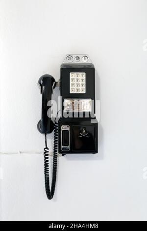 Payphone nero pulsante vintage appeso al muro Foto Stock