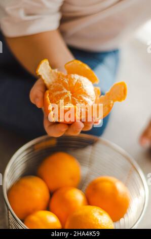 il bambino tiene la mandarino pelata nel cestino Foto Stock