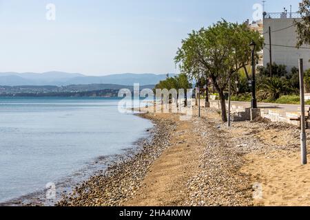 in grecia c'è una spiaggia di sabbia, alcuni pioli arrugginiti che escono dalla sabbia e si godono la vista sull'oceano e sulle montagne sul retro. anche gli alberi sono nella foto. Foto Stock