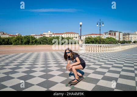 skater ragazza pattinare e saltare sulla terrazza mascagni a livorno, italia. il suo ampio belvedere sinuoso verso il mare con una superficie di pavimentazione di 8700 mq come una scacchiera e 4,100 balaustre Foto Stock