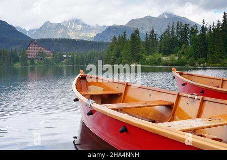 Paesaggio montano con barche rosse sul lago. High Tatra, Slovacchia, Europa Foto Stock