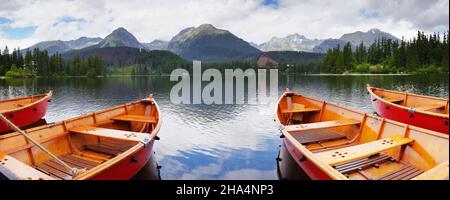 Panorama montano con barche rosse sul lago. Lago Strbske Pleso, Tatra Alto, Slovacchia, Europa Foto Stock