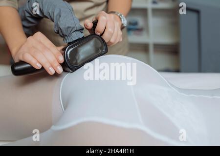 Immagine ravvicinata del terapista estetista rende GPL Trattamento massaggio alla giovane donna in bianco trasparente tuta, giacenti presso la beauty spa clinica. Focus sulle mani Foto Stock
