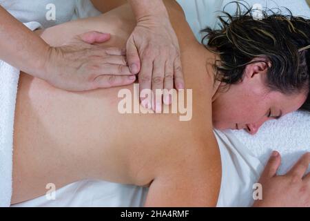 Donna massaggiatrice con i palmi delle mani sulla schiena di un'altra donna, dandole un massaggio terapeutico o reiki Foto Stock