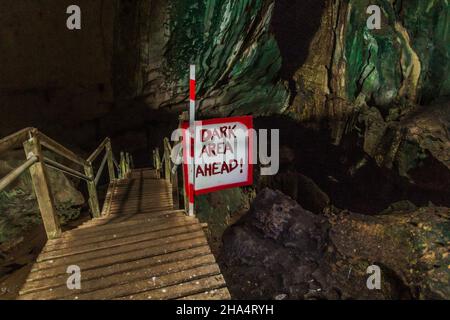 Insegna Dark Area davanti alla Grande Grotta nel Parco Nazionale di Niah, Malesia Foto Stock