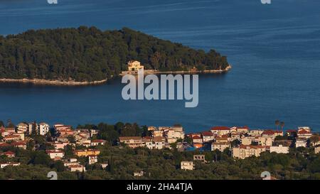 grecia,isole greche,isole ionie,lefkada o lefkas,baia di nidri,vista dall'alto al posto nidri in primo piano e l'isolotto boscoso madouri con una villa su di esso in mezzo distanza, mare blu scuro, senza cielo Foto Stock