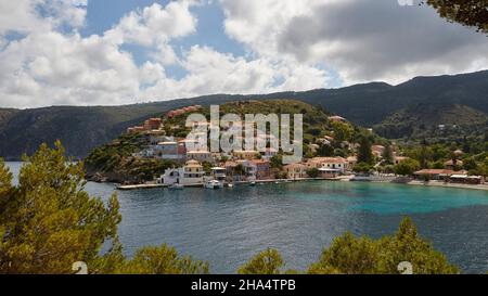 grecia,isole greche,isole ionie,cefalonia,assos,posto sulla costa occidentale,fortezza veneziana,via per la fortezza,vista su place assos,azzurro cielo con nuvole grigio e bianco,blu mare e turchese,alberi in primo piano Foto Stock