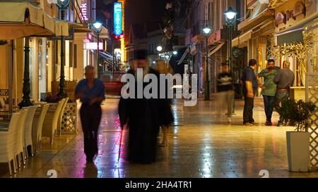 grecia,isole greche,isole ionie,cefalonia,argostoli,capitale di cefalonia,zona pedonale,foto notturne,marciapiede brilla dalla pioggia,persone sfocate,papa in primo piano,riflessi luce sulla terra Foto Stock