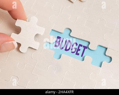 Firma a mano Budget. Parola scritta su una stima di entrate e spese per un periodo di tempo stabilito costruire un bianco incompiuto Jigsaw modello Foto Stock