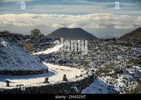 Vista all'aperto della Sicilia in inverno montagna tortuosa strada sterrata coperta di neve nel Parco dell'Etna Foto Stock