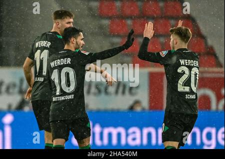 10 dicembre 2021, Baviera, Regensburg: Calcio: 2. Bundesliga, Jahn Regensburg - Werder Bremen, Matchday 17, Jahnstadion Regensburg. Leonardo Bittencourt (centro) di Werder festeggia con i suoi compagni di squadra Niclas Füllkrug (l) e Romano Schmid dopo aver segnato 1:1 contro Regensburg. Foto: Armin Weigel/dpa - NOTA IMPORTANTE: In conformità con le norme della DFL Deutsche Fußball Liga e/o della DFB Deutscher Fußball-Bund, è vietato utilizzare o utilizzare fotografie scattate nello stadio e/o della partita sotto forma di immagini di sequenza e/o serie di foto di tipo video. Foto Stock