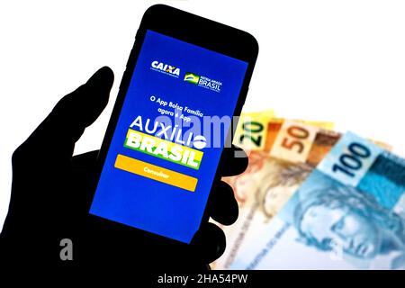Barcellona, Catalogna, Spagna. 9th Dic 2021. In questa foto è illustrata un'app Auxilio Brasil visualizzata su uno smartphone con note reali brasiliane sullo sfondo. (Credit Image: © Thiago Prudencio/DAX via ZUMA Press Wire) Foto Stock