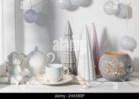 Figurine in ceramica di alberi di Natale color pastello, un angelo di fedi bianco, una ghirlanda di palle fatte di fili decorano la stanza prima di Natale Foto Stock