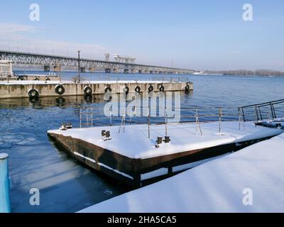 Vista invernale dei moli abbandonati del fiume sul Dnieper. Arrugginite nella neve. I moli sono coperti di neve. Foto Stock