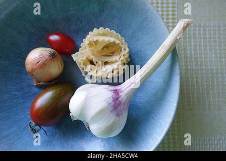 recipiente blu con verdure, aglio, pomodori, spaghetti e cipolle, ingredienti per un piatto di pasta. Foto Stock