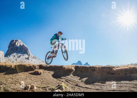 e-biker in azione salta con la sua bicicletta,paesaggio autunnale,dolomiti,san vito di cadore,belluno,veneto,italia Foto Stock