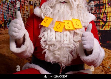 Babbo Natale con note adesive incollate al mento che dice 2022. Foto Stock