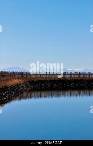 bacino di stoccaggio costruito nel 2020, di fronte alle montagne delle dolomiti,recinzione,specchio,nuvole trasparenti,bressanone,alto adige,italia Foto Stock