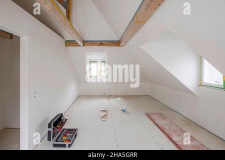 cantiere, ristrutturazione e ristrutturazione di un appartamento, camera vuota nella mansarda con soffitto a travi in legno e dormitorio Foto Stock