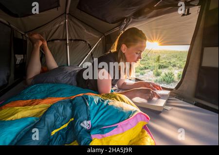 Croazia, Zrmanja, Winnetou, giovane donna di sera nella tenda del tetto su un veicolo fuoristrada Foto Stock