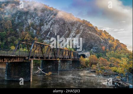 Splendida vista su un ponte sull'acqua, alberi e un cielo blu nuvoloso nella città di Harpers Ferry Foto Stock