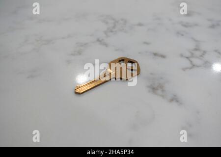 Vista ad angolo di una semplice chiave in bronzo sulla parte superiore di un bancone in marmo bianco Foto Stock