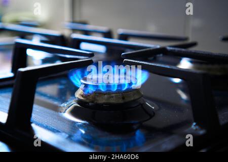 La fiamma blu del piano cottura a gas produce emissioni di gas serra. Grata di stufa da cucina su un bruciatore alimentato da gas naturale combustibile o syngas, propano Foto Stock