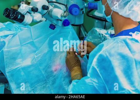 Primo piano dell'operazione di oftalmologia. Il medico del chirurgo mani in guanti che eseguono la correzione della visione dell'occhio del laser. Foto Stock