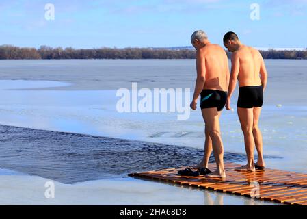 Sport invernali di nuoto. Indurimento. Gli uomini nuotano in un fiume d'inverno coperto di ghiaccio durante l'Epifania Ortodossa. Dnipro città, Dnepropetrovsk Foto Stock