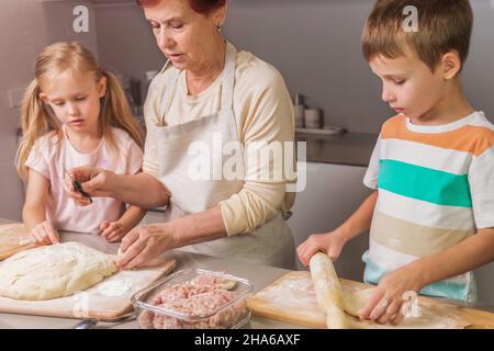 nonna e nipoti stanno preparando una torta per la vacanza Foto Stock