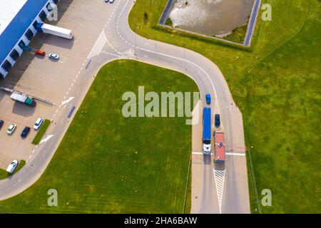 Vista aerea del magazzino con i camion che guidano verso il centro logistico. Contesto industriale. Logistica dall'alto. Foto Stock