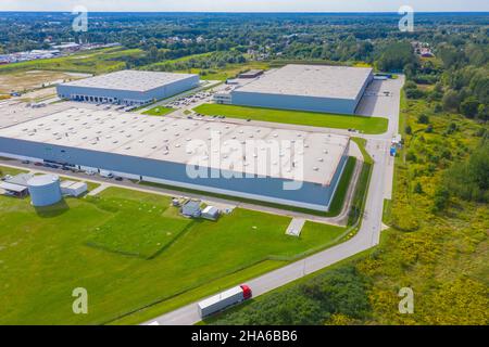 Vista aerea del magazzino con i camion che guidano verso il centro logistico. Contesto industriale. Logistica dall'alto. Foto Stock