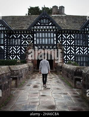 Ammirando la facciata tudor di questo maniero del National Trust. Speke Hall è una casa padronale Tudor con pareti in legno a Speke, Liverpool, Inghilterra. Foto Stock