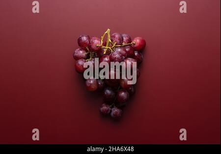 Globo rosso con gocce d'acqua poste su sfondo rosso scuro opaco. Vista dall'alto. Foto Stock