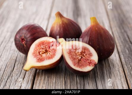 Molti fichi e fichi tagliati sul vecchio sfondo in legno. Foto Stock