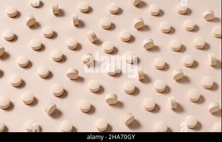 Pillole beige su sfondo beige. Concetto di prodotti farmaceutici e integratori. Foto Stock