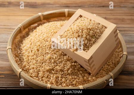 Rosolare il riso in una scatola di legno e il colander di bambù posto su un fondo di legno. Foto Stock