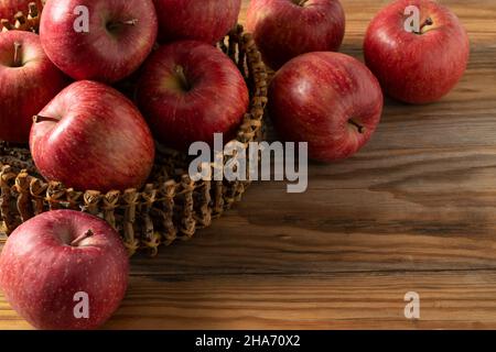 Un sacco di mele in un cesto di legno posto sullo sfondo di legno. Foto Stock