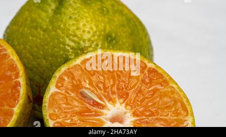 Frutta fresca di mandarino verde e succo su sfondo bianco, frutta sana Foto Stock